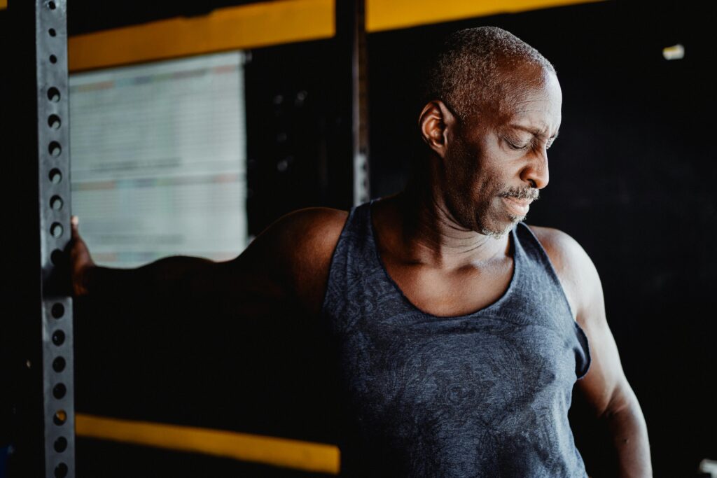 A senior man in active wear stretching in a gym, promoting fitness and well-being.