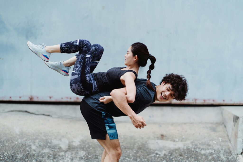Energetic couple having fun with playful exercises outdoors, showcasing teamwork and fitness.