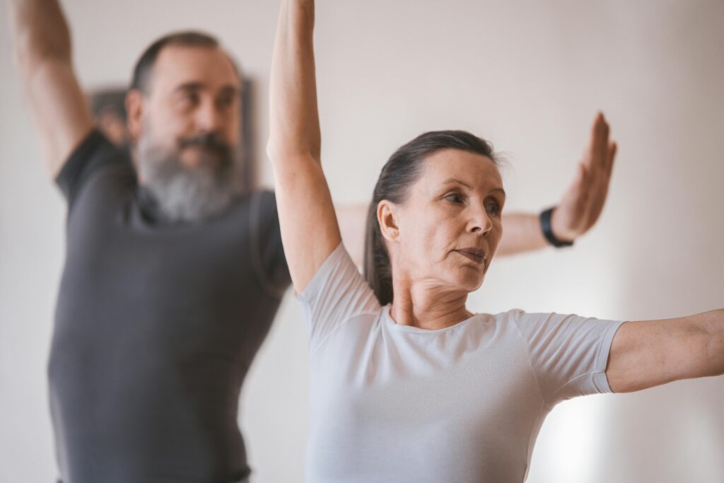 Senior adults in a yoga session indoors, focusing on stretching and balance.