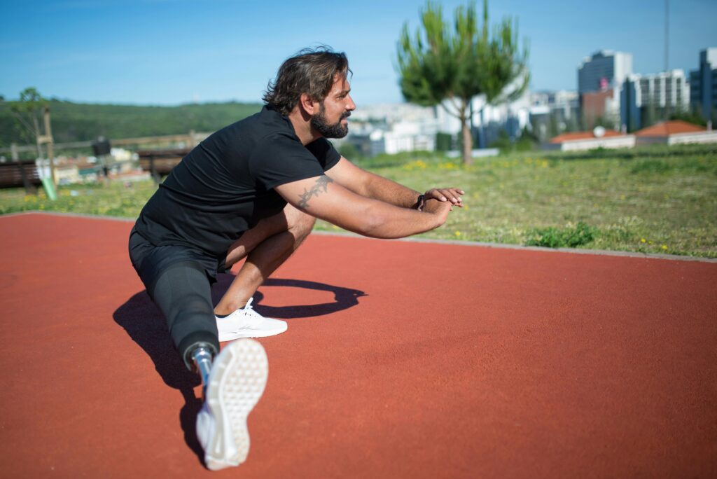 An amputee man sitting and stretching in a sunny outdoor park in Portugal.