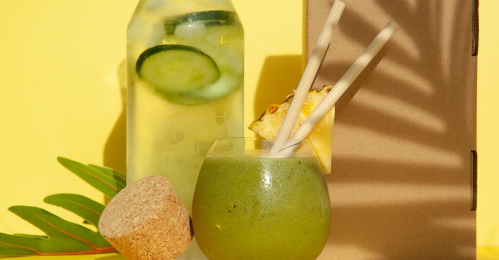 Delicious green smoothie with pineapple and cucumber water against a yellow backdrop. Perfect summer refreshment.