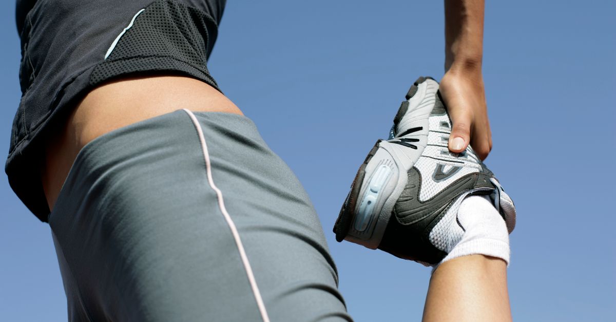 Fitness enthusiast stretching her leg in sportswear on a sunny day.