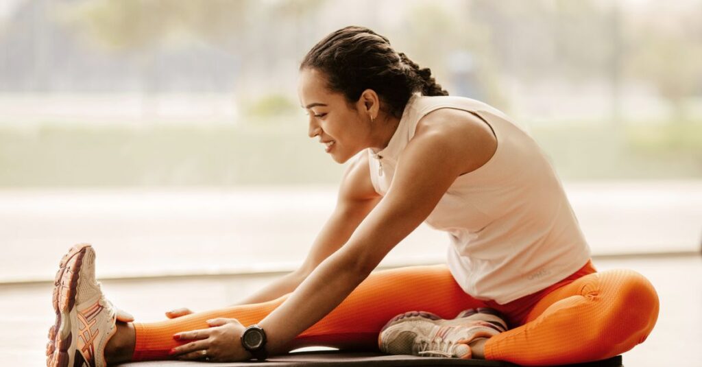 A woman performing a hamstring stretch indoors, promoting fitness and flexibility.