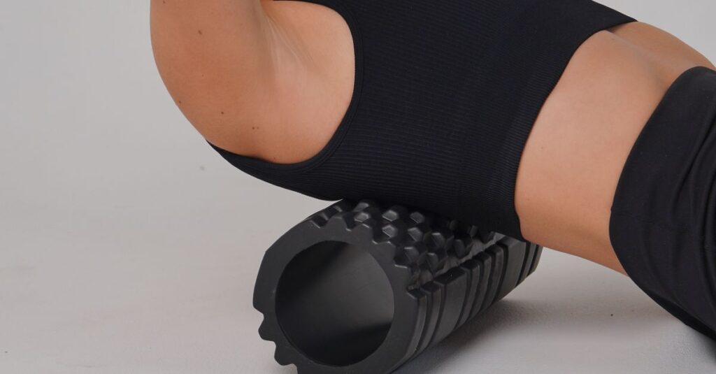 Adult woman practicing workout therapy with a foam roller on a white background.