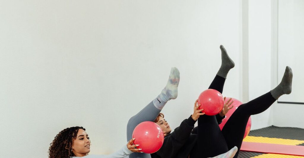 Two women engaging in a fitness routine with pink exercise balls at a modern gym.