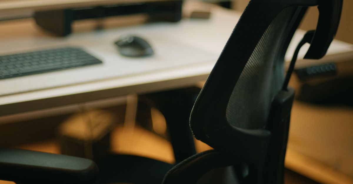 A sleek ergonomic chair and desk with computer setup, highlighting a modern workspace.