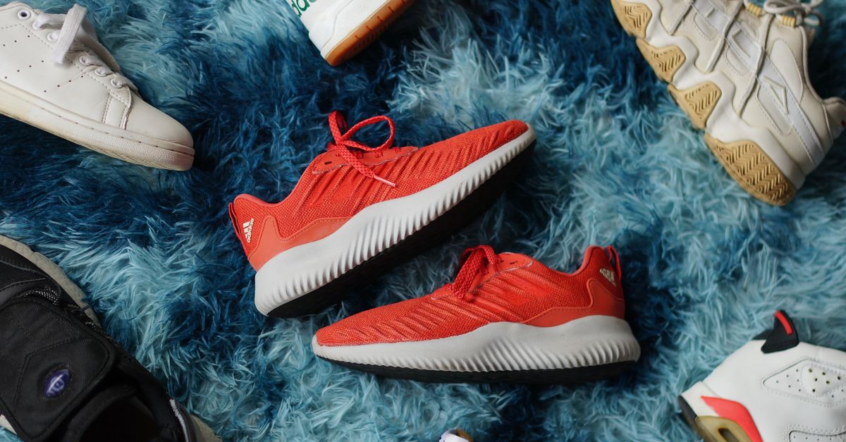 Colorful sneakers arranged on a fluffy blue rug, showcasing diverse casual shoe styles.