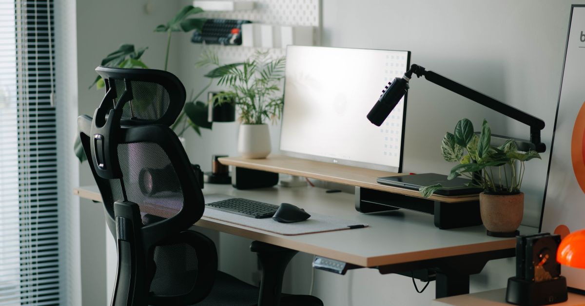 Stylish home office setup with ergonomic chair, plants, and modern desk accessories.