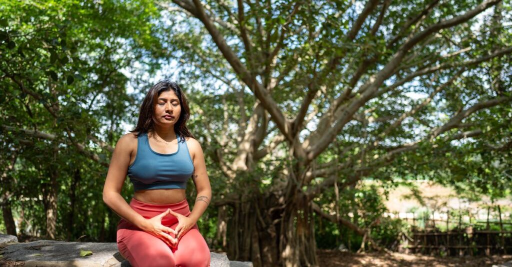 A woman practicing meditation under a banyan tree in nature, promoting tranquility and mindfulness.