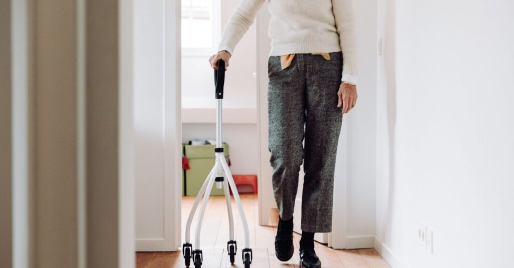 Senior adult walking indoors with a rollator, promoting mobility and independence.