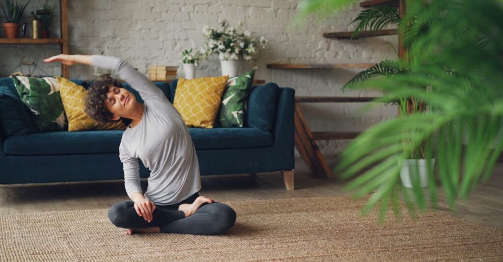 Woman doing a yoga pose on a rug in a cozy living room with plants.