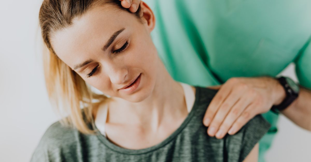 Crop professional male massage therapist in green medical uniform doing therapeutic neck massage on content female patient wearing casual clothes
