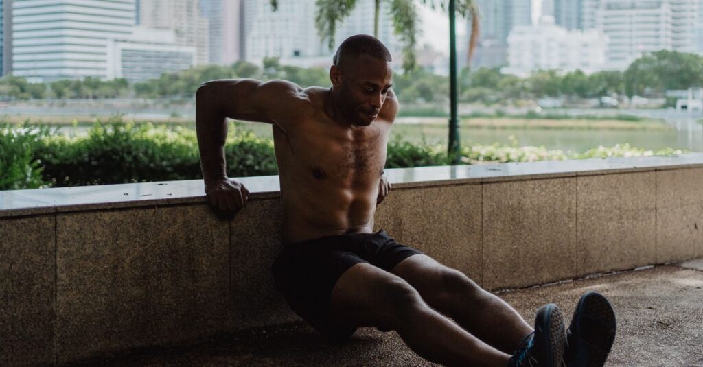 An athletic man engages in a tricep dip workout in an urban park setting.