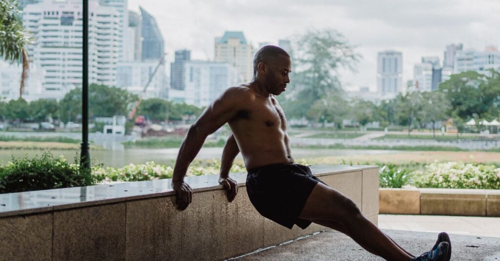 Bald man performing a strength exercise outdoors in an urban park setting, showcasing fitness and determination.