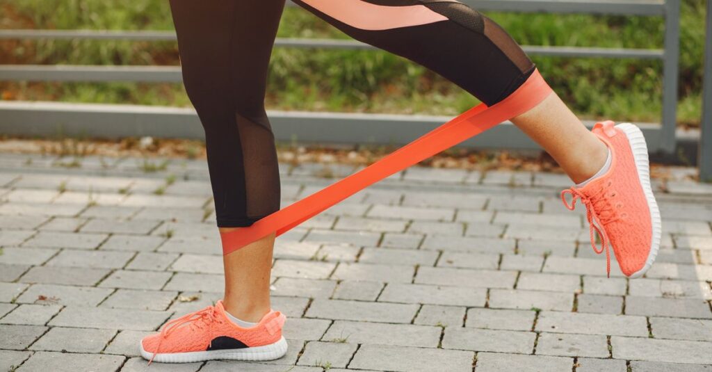 Close-up of a woman exercising with a resistance band in a park.