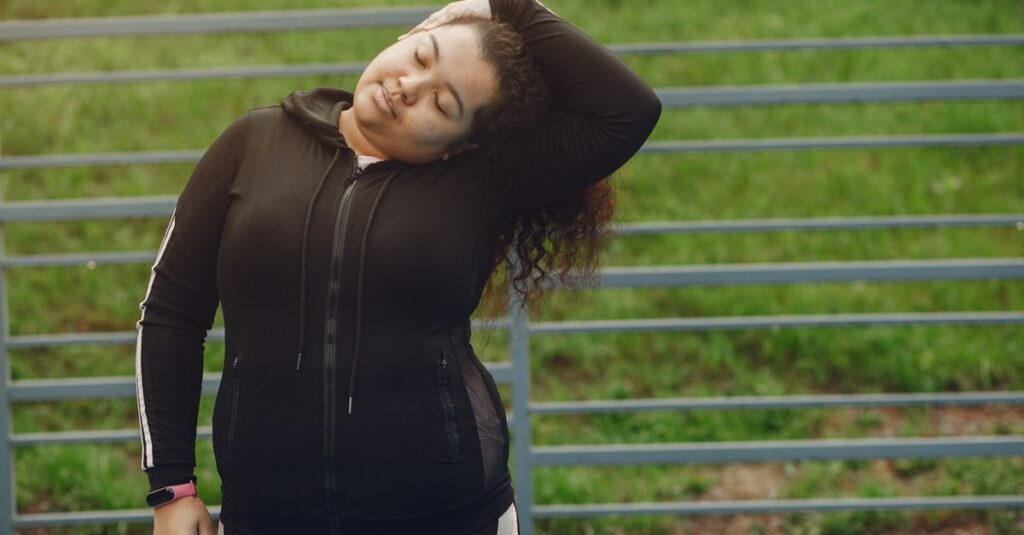 Woman in sportswear stretching outdoors with closed eyes and peaceful expression.