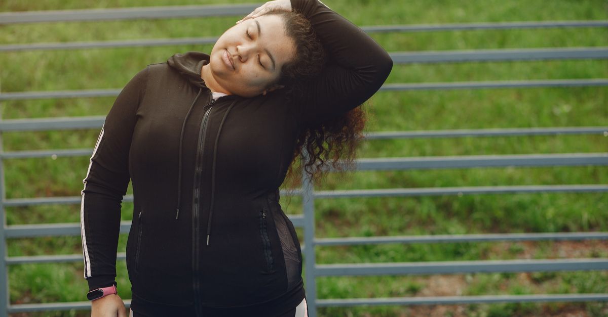 Woman in sportswear stretching outdoors with closed eyes and peaceful expression.