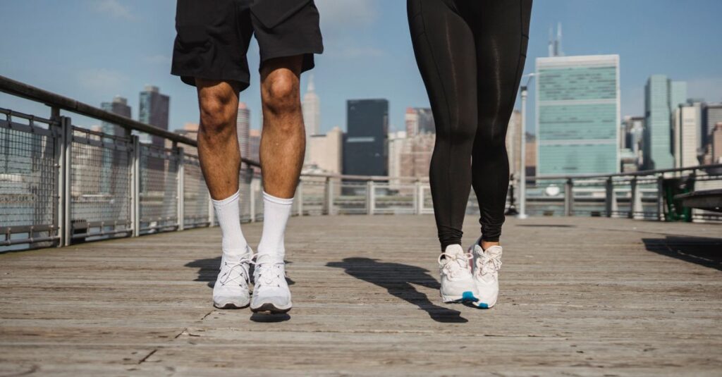 A man and woman jogging on a boardwalk with a city skyline in the background. Dynamic fitness and urban lifestyle.