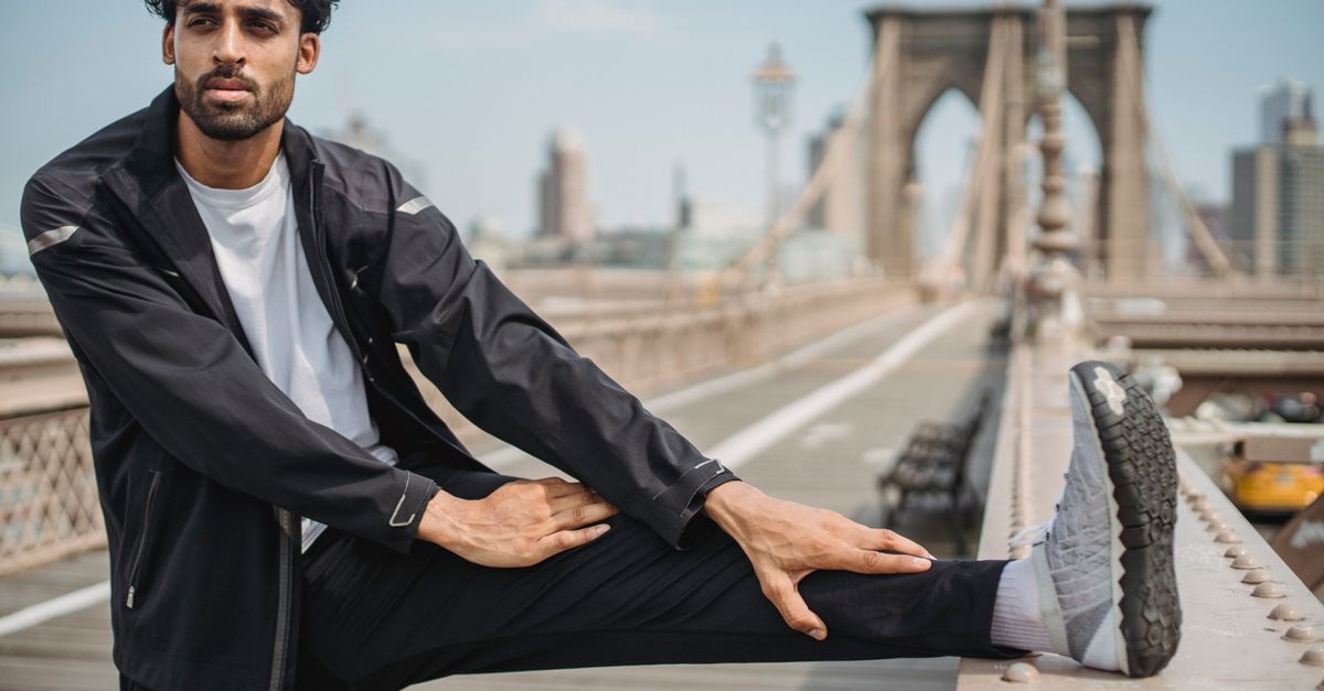 Man in sportswear stretching on the iconic Brooklyn Bridge, NYC.