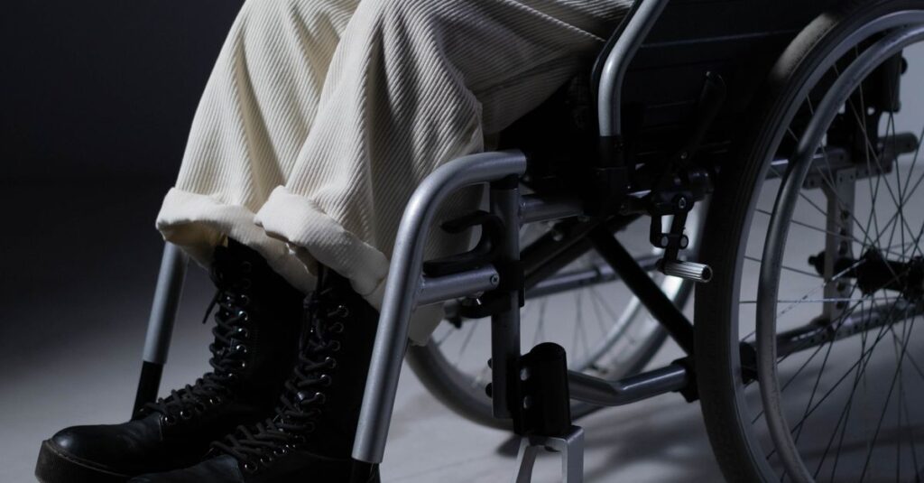 An individual seated in a wheelchair dressed casually indoors, focusing on mobility and independence.