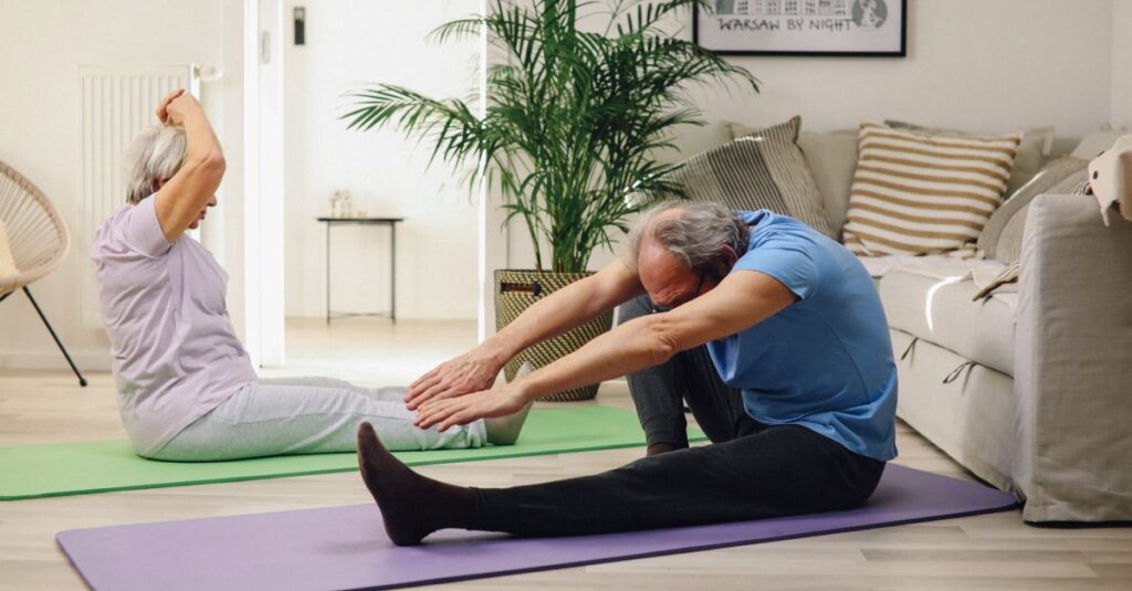 Elderly couple practicing yoga at home, promoting wellness and healthy lifestyle.