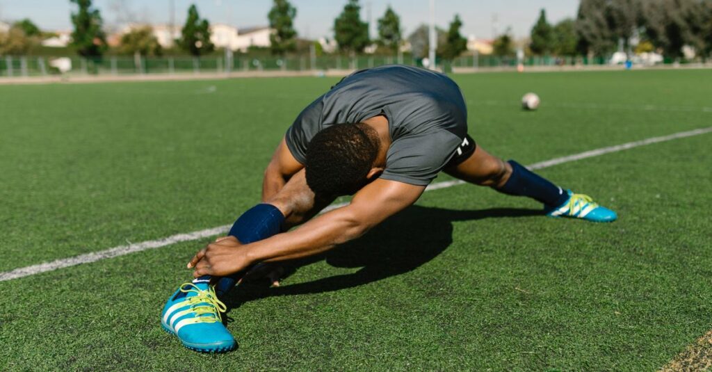 Black male athlete stretching on a soccer field, showcasing flexibility and athleticism.