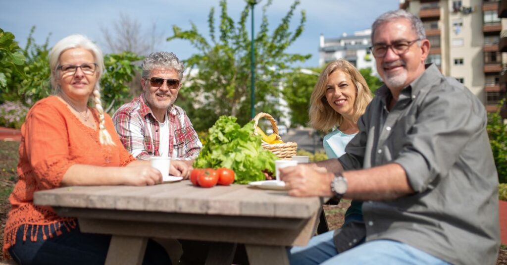 Happy group of seniors enjoying a picnic outdoors with fresh vegetables.