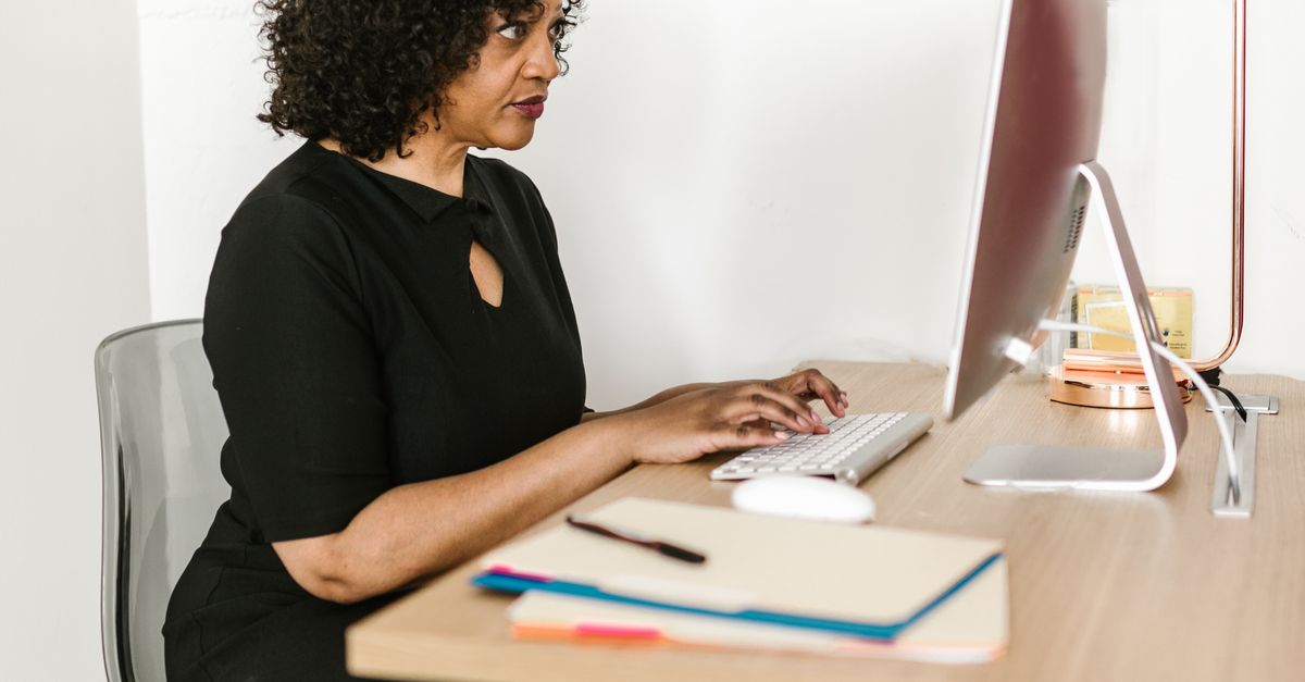 African American woman typing on computer in office, focusing on work.