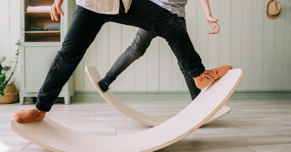 Two kids playing on wooden balance boards indoors, focusing on balance and mindful activities.