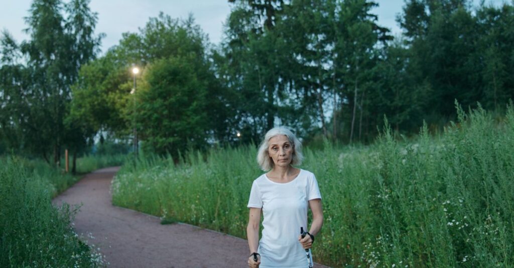 Senior woman enjoying a Nordic walk in lush green park setting.