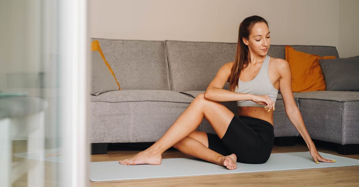 Woman practicing yoga indoors on a mat, embodying fitness and tranquility.